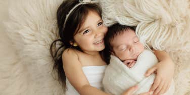 toddler sister hugging infant brother