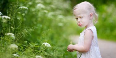 angry toddler girl picking flowers