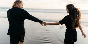 guy and girl holding hands walking on the beach