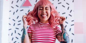 Woman with tattoos, pink hair and smile on her face