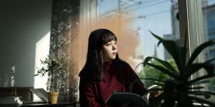 woman sitting by window looking outside